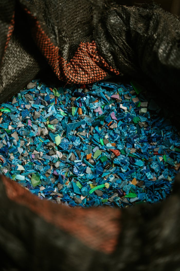 Detailed close-up of colorful recycled plastic fragments in a black sack, showcasing sustainability.